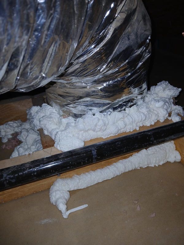 Spray foam sealing around a duct boot in an attic