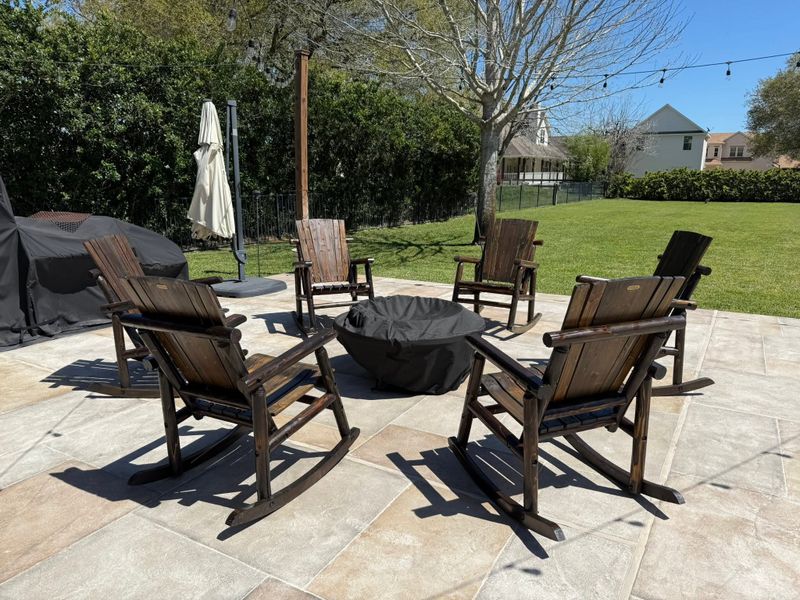Wooden rocking chairs around a fire pit on a stone patio
