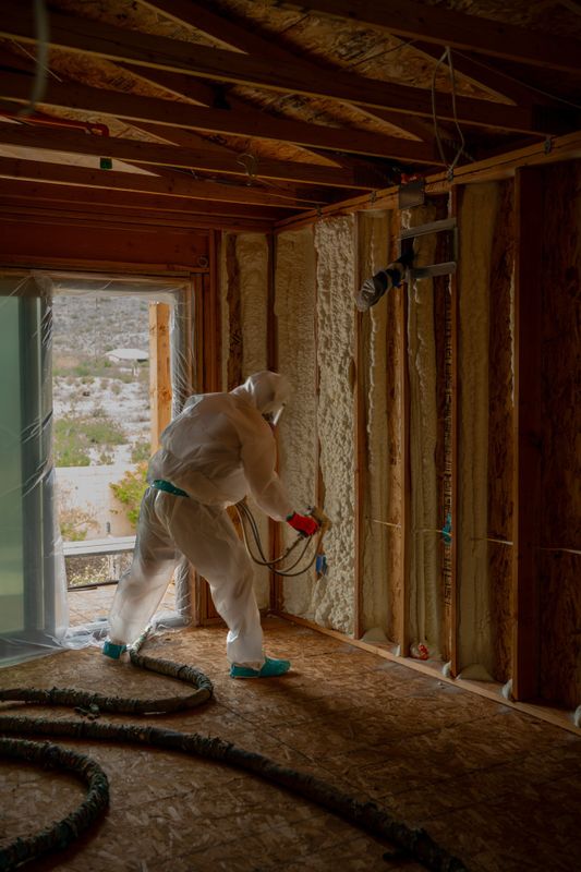 Foam Pro Insulation crew member in a white suit spraying foam into wall cavities