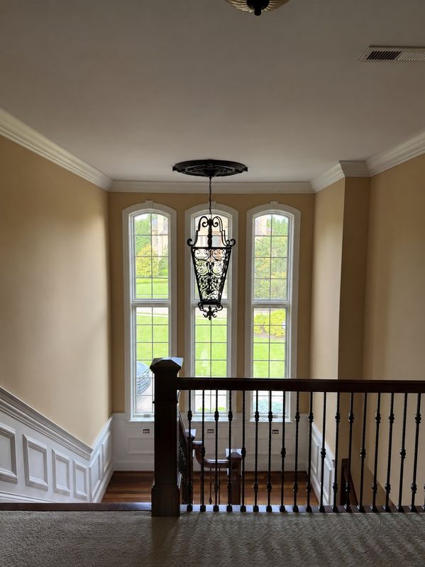 Painted stairwell with arched windows, crown molding and a wrought iron railing