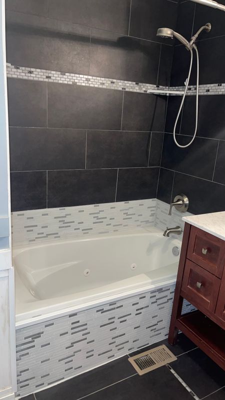 Finished bathroom with charcoal tile tub surround and cherry vanity