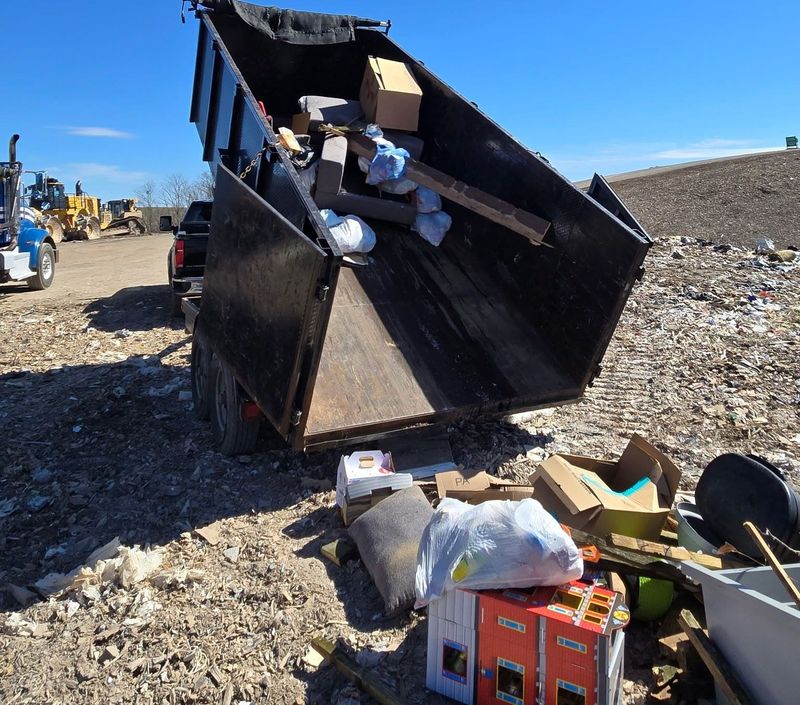 Black dump trailer loaded with junk at a construction site