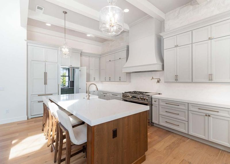 Light gray refinished kitchen cabinets around a white quartz island