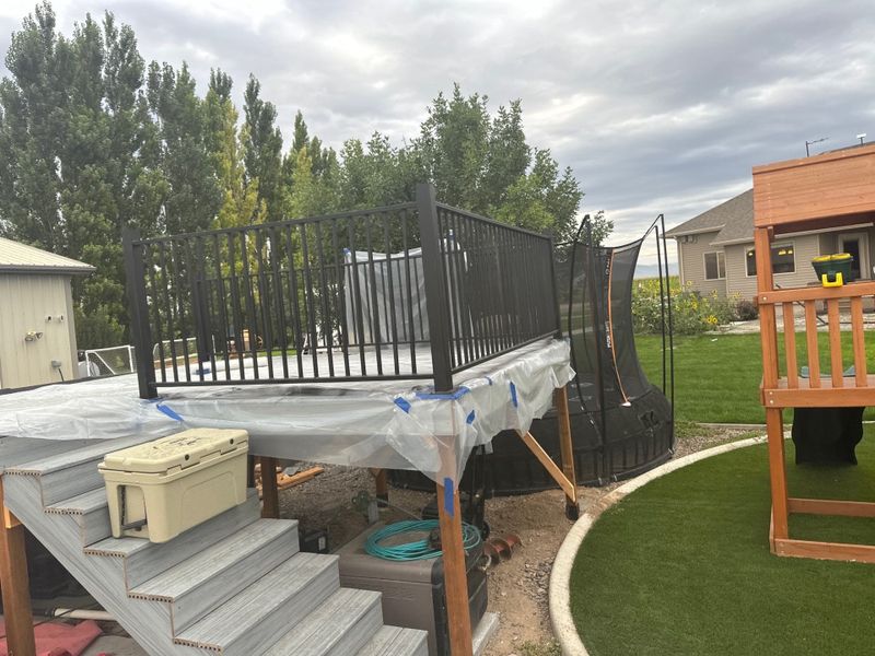 Raised deck with black railing and stairs beside a backyard playset