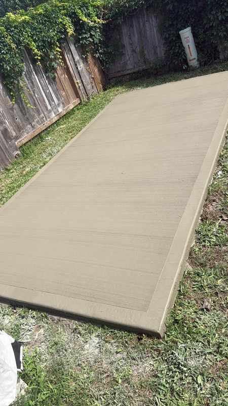 Newly finished concrete walk beside a wooden fence