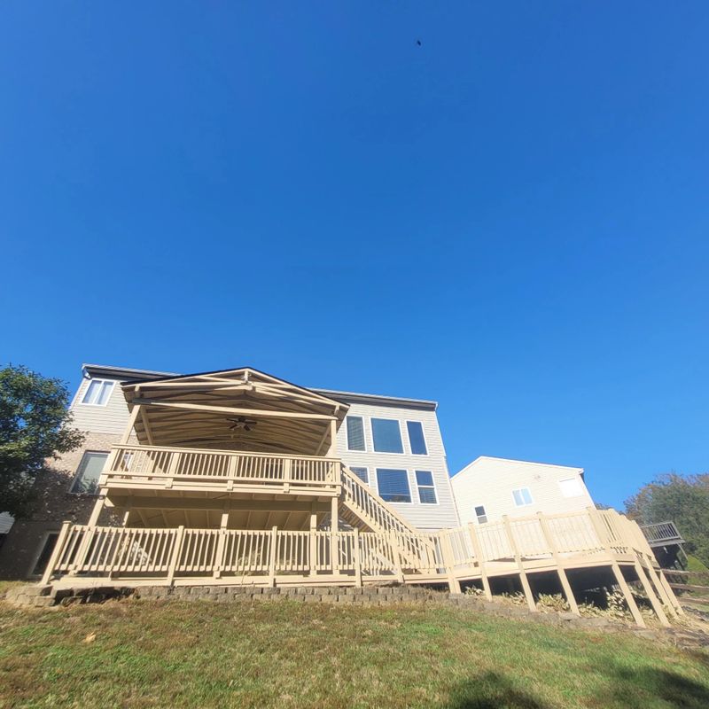 Large stained deck and railing under a clear blue sky