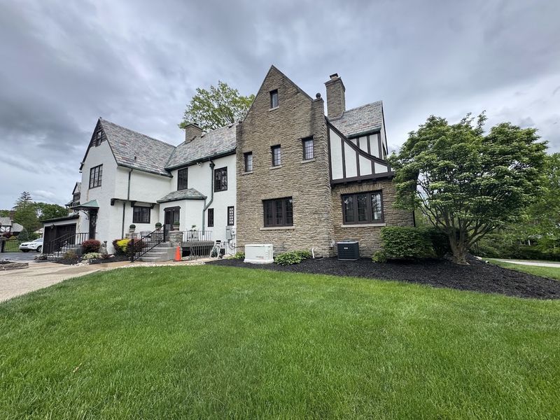 Tudor-style home with a white brick wing next to a stone section