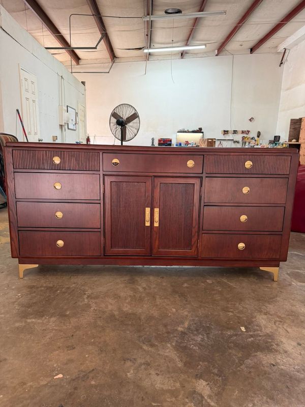 Dark wood sideboard with brass drawer pulls in a workshop