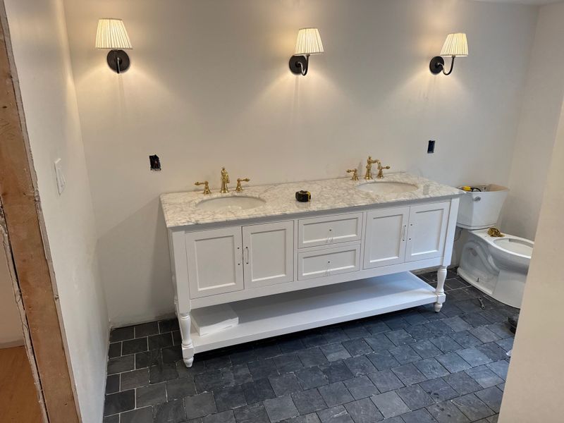 New bathroom with a white double vanity, wall lights and a dark slate-look tile floor