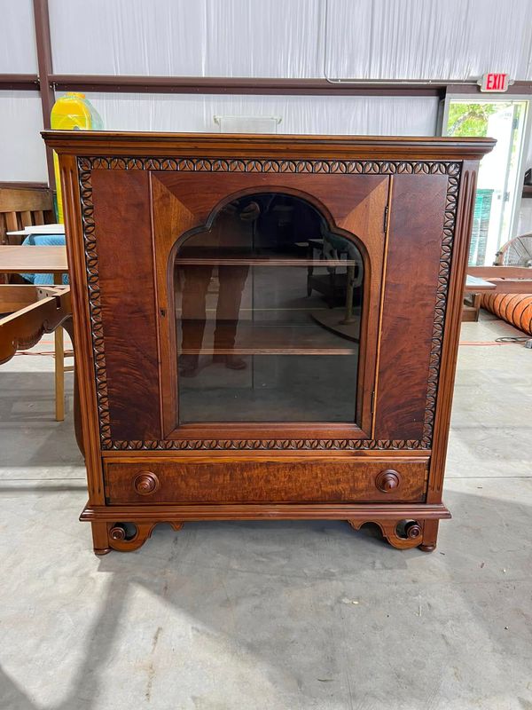 Antique wooden cabinet with a glass door and carved trim