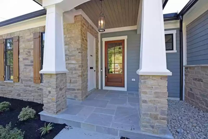 Wood shutters beside a stone entry with a covered porch