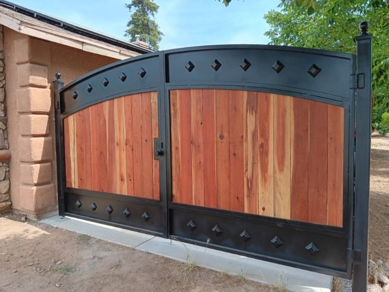 Arched steel and redwood driveway gate by J&C Fencing