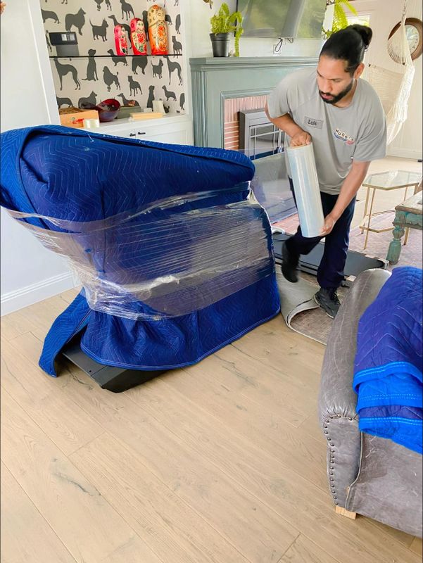Crew shrink-wrapping a couch before the move