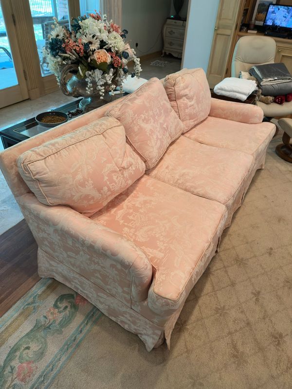 Pink floral upholstered sofa with loose back cushions in a living room