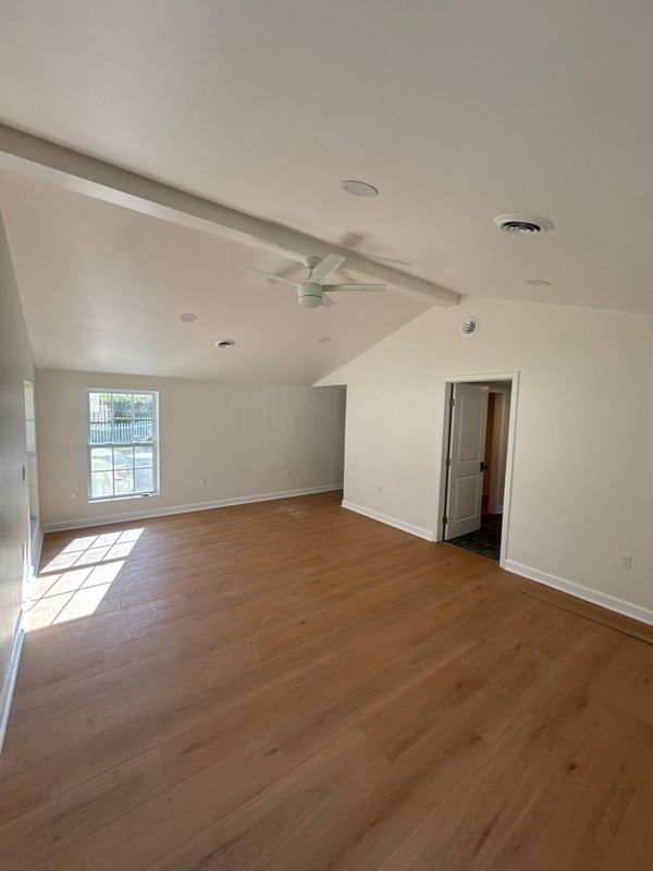 Finished bedroom in the addition with a warm wood-look floor and white trim