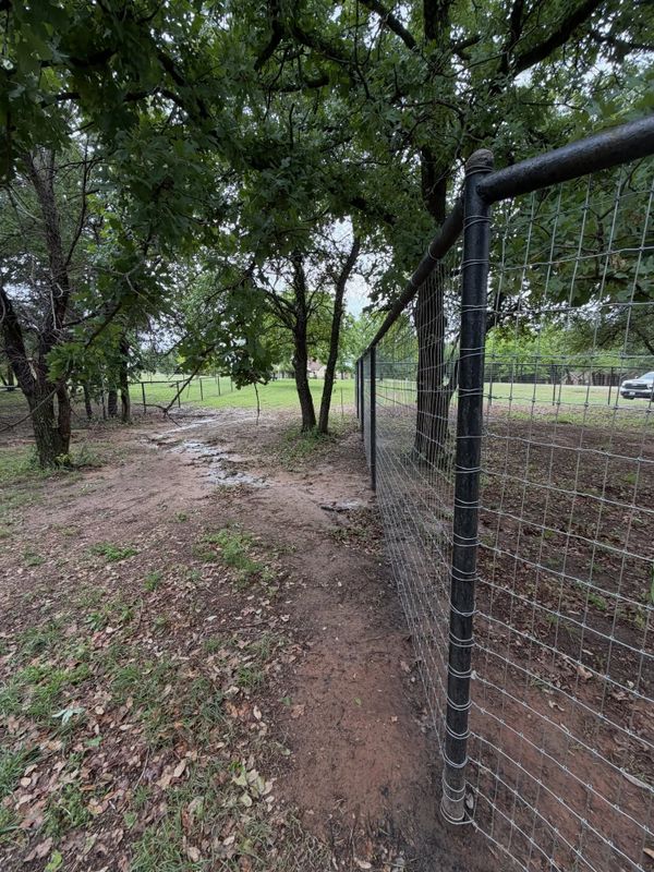 Wire field fencing installed along a wooded property line near Granbury, Texas