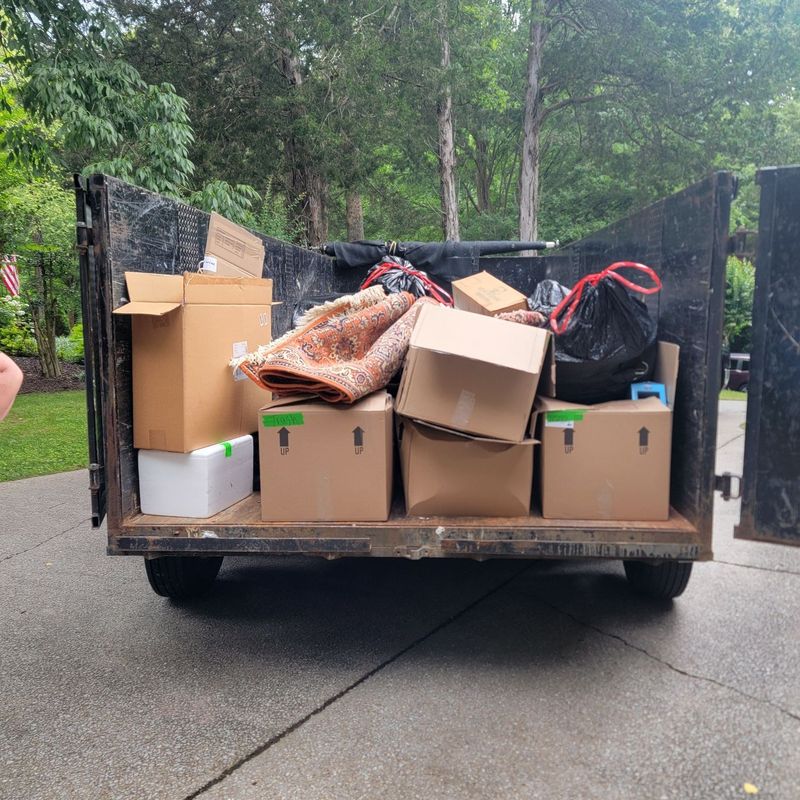 Trailer of boxes and bags in a driveway after a cleanout