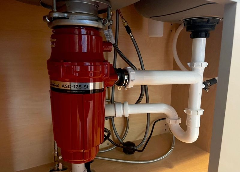 New garbage disposal under a kitchen sink with fresh white drain lines