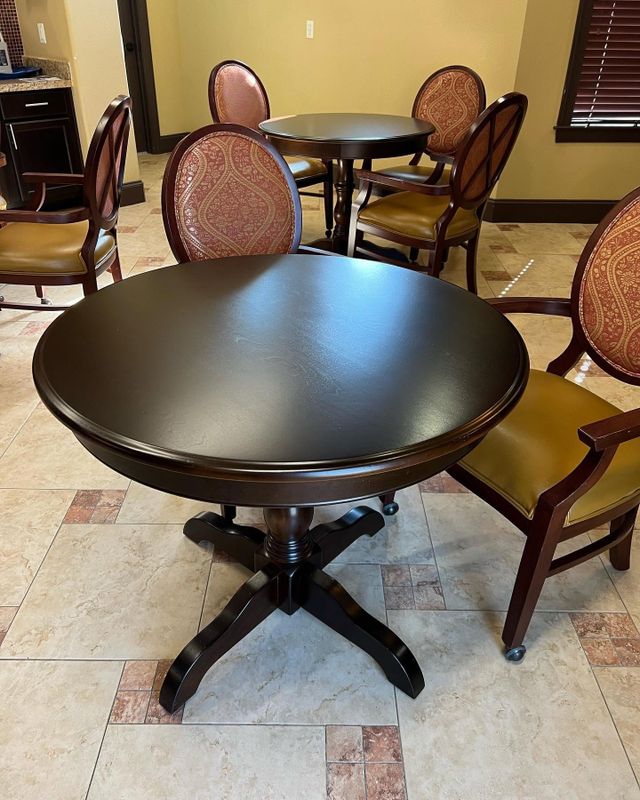 Round dark-finish wood table with upholstered chairs on a tile floor