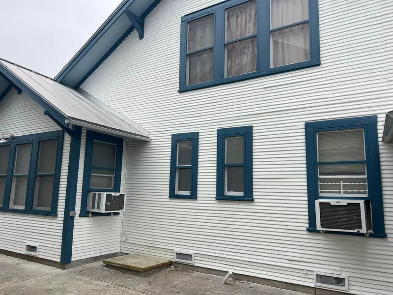 Side elevation of the same craftsman home, white siding with deep teal window trim