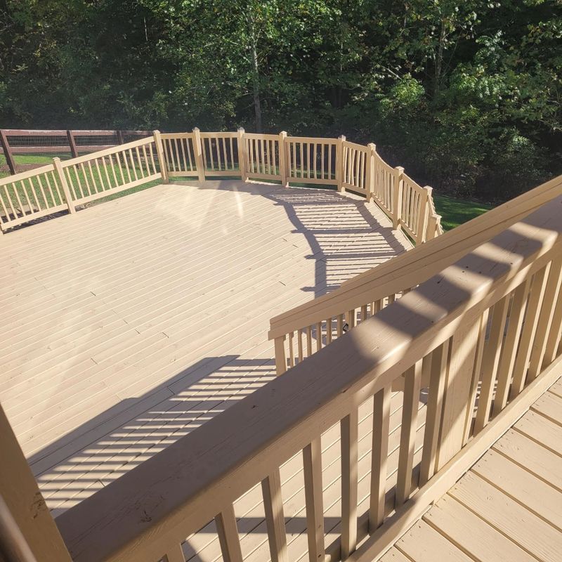 Tan stained deck with a repaired railing running around the edge