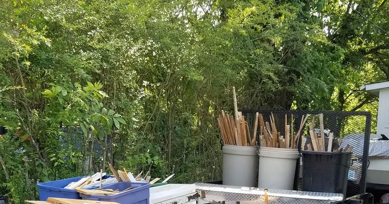Trailer with yard tools and buckets by greenery