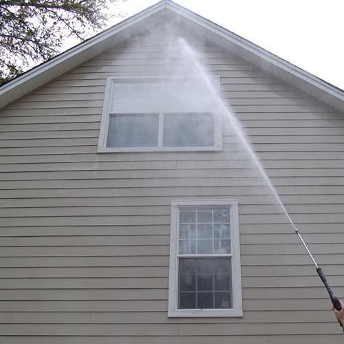 Gentle low-pressure rinse on vinyl siding and windows during a house washing