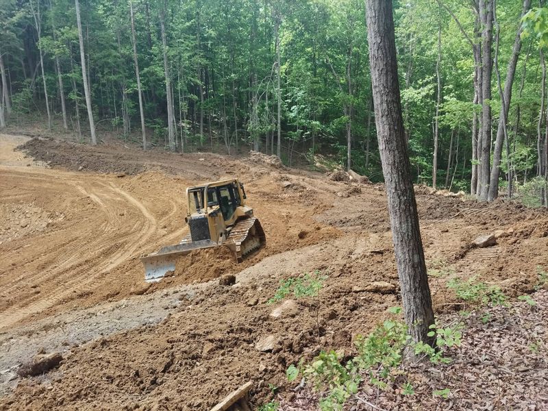 Bulldozer working a wooded slope while clearing ground for a new pond