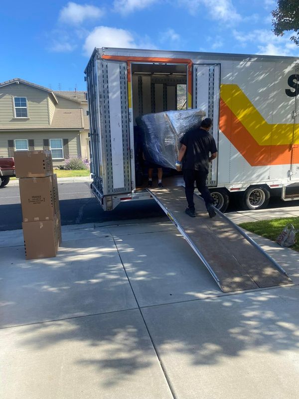 Mover with a dolly at a truck ramp loading a wrapped item