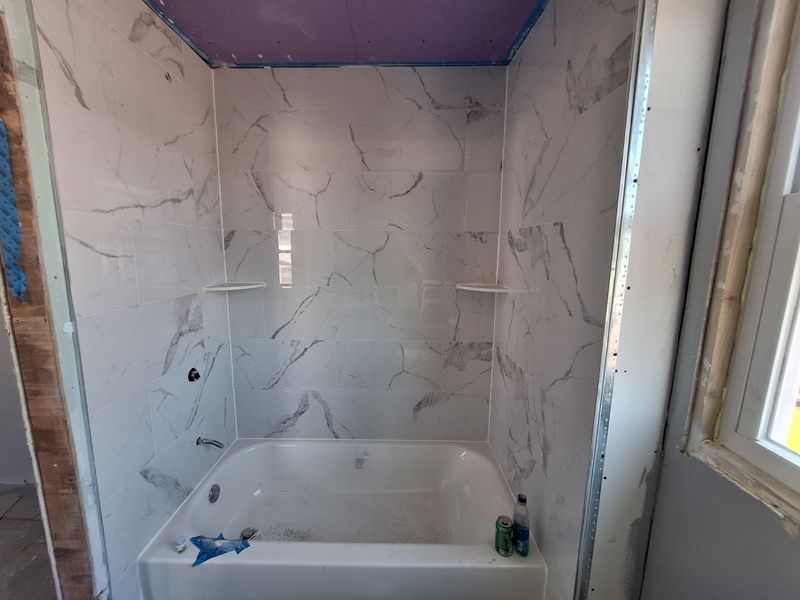Bathroom renovation with large-format stone-look tile around a bathtub