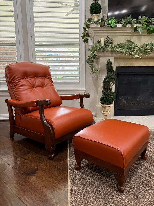 Orange leather recliner and matching ottoman beside a fireplace