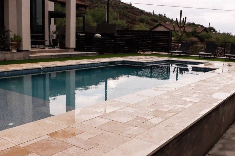 Travertine paver pool deck beside a modern Phoenix home