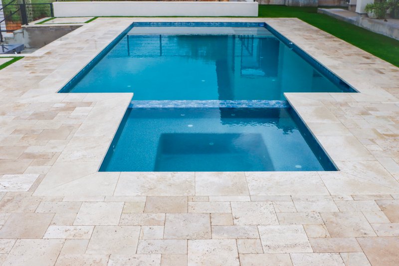 Custom pool with travertine paver decking and turf