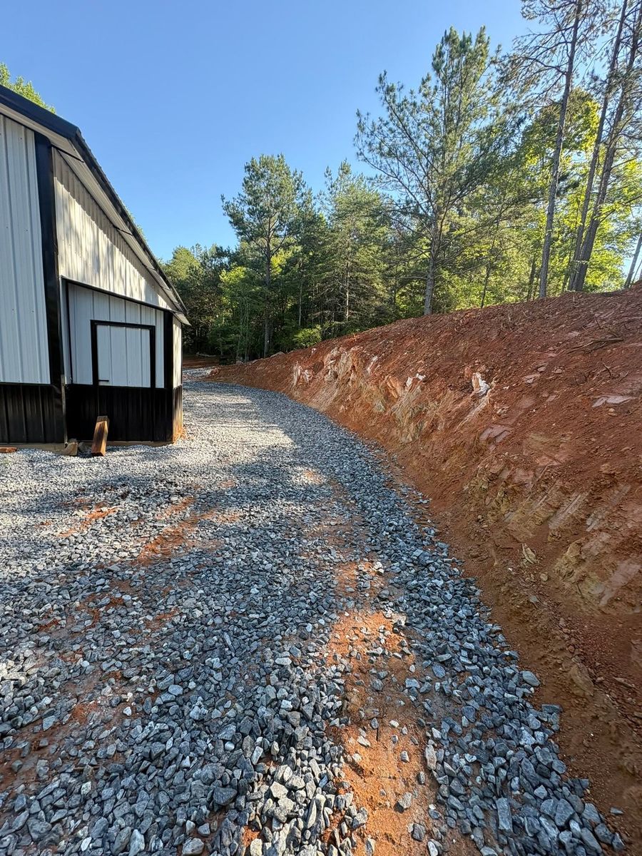 Bare cut bank beside a metal building and gravel drive