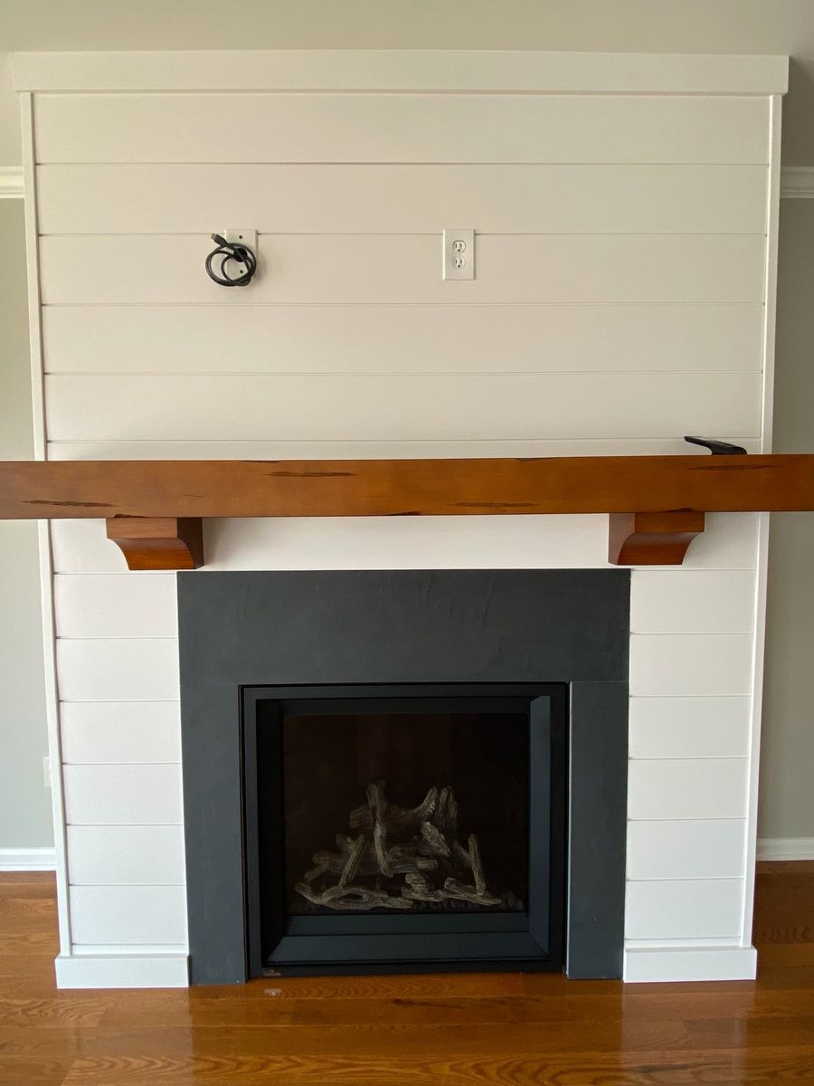 Shiplap fireplace wall painted white with a wood mantel