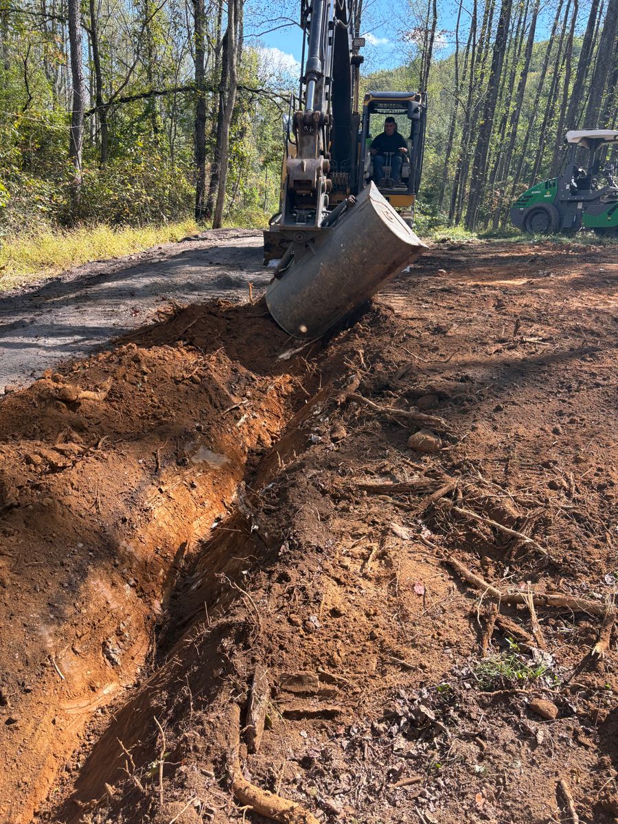 Excavator bucket opening a drainage trench
