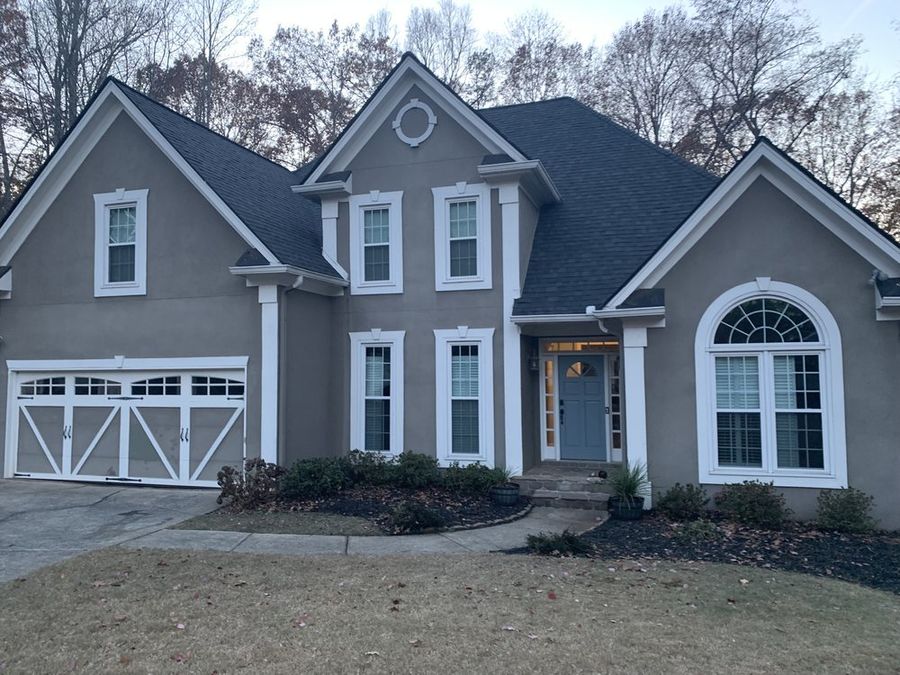 Gray two-story with carriage garage doors and a new roof