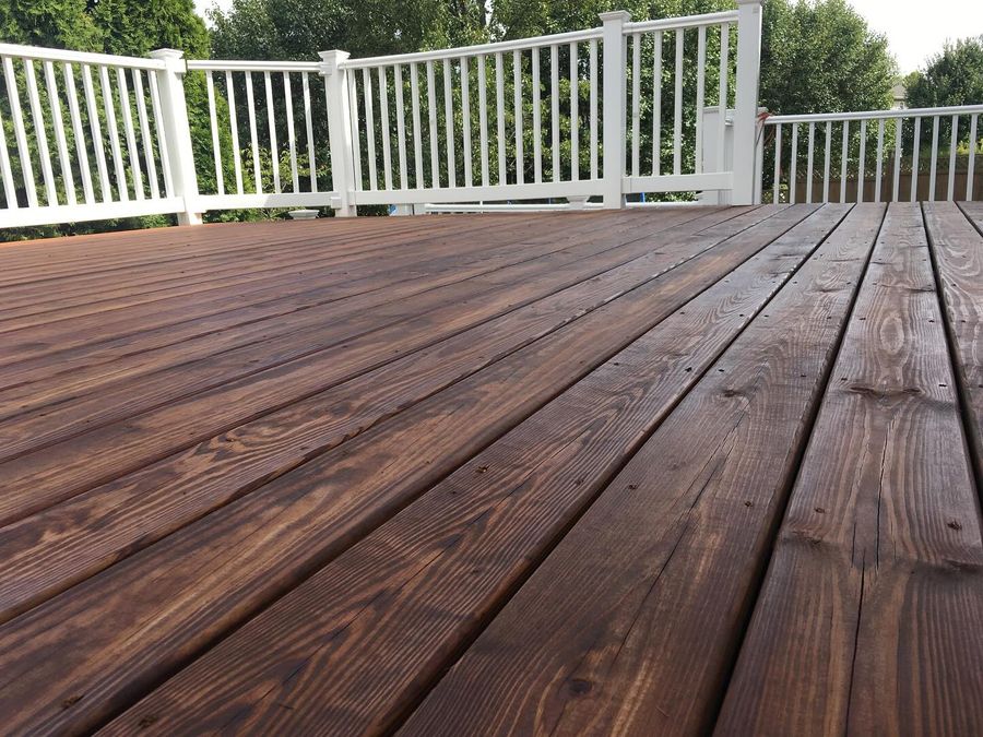 Stained deck with white railings and a lawn beyond