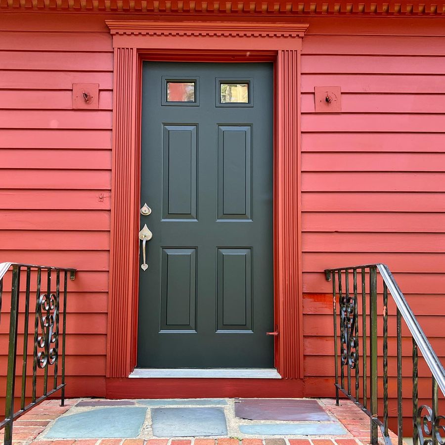 Red clapboard house with a dark green front door
