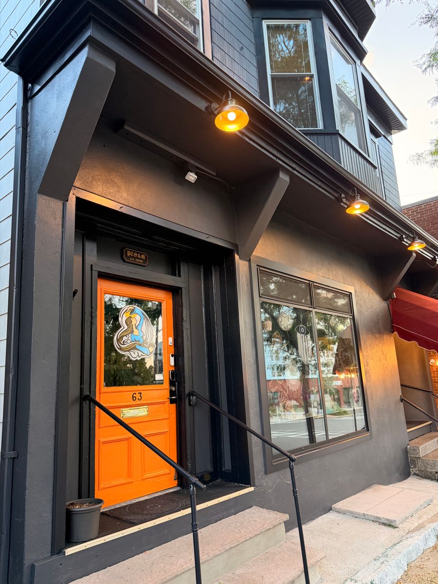 Storefront painted dark with a bright orange door