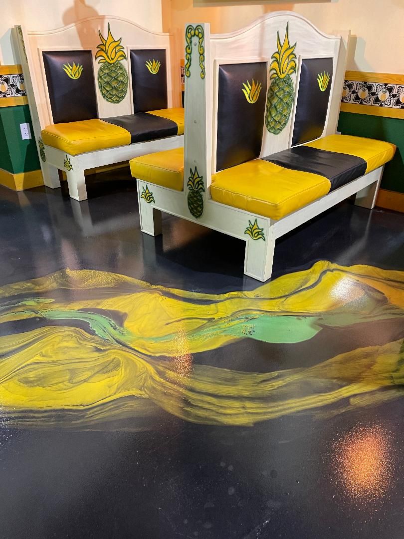 Yellow and green metallic epoxy restaurant floor beside pineapple booths