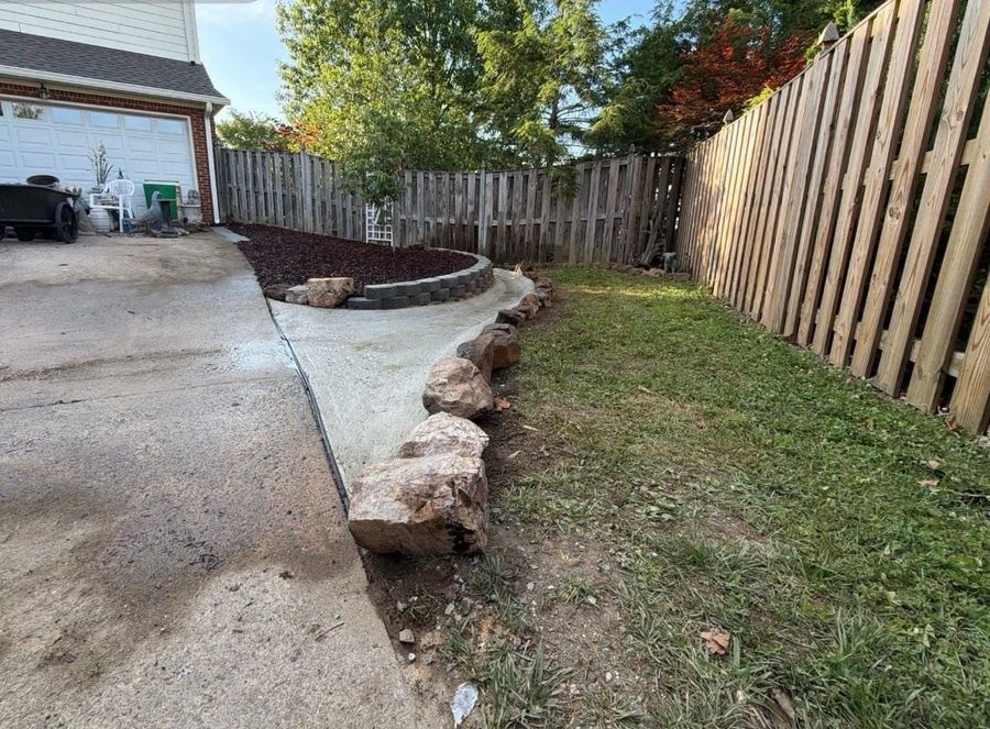 Block wall and boulder edge along a new concrete apron