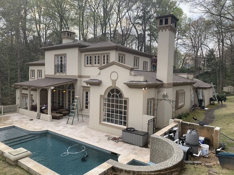 Stucco home with a new roof, seen from the pool deck