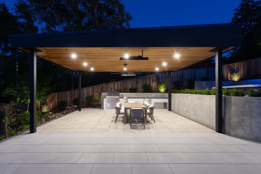 Steel-framed pavilion with a timber-lined ceiling over the outdoor kitchen and dining table