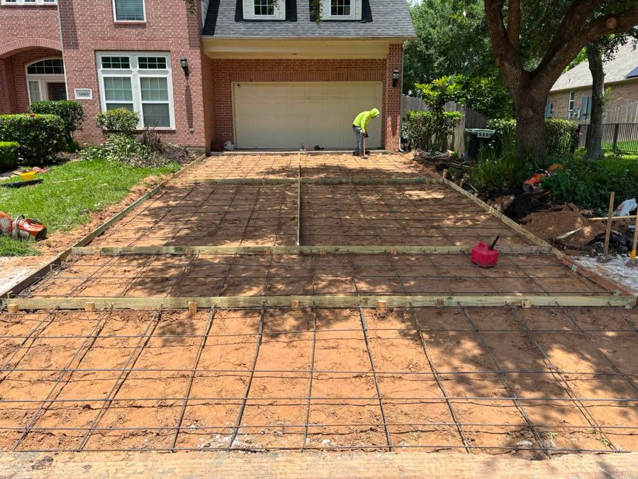 Wood forms and a rebar grid set on a driveway pad before the pour