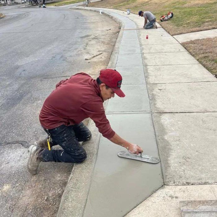 Crew member hand-finishing a new concrete sidewalk