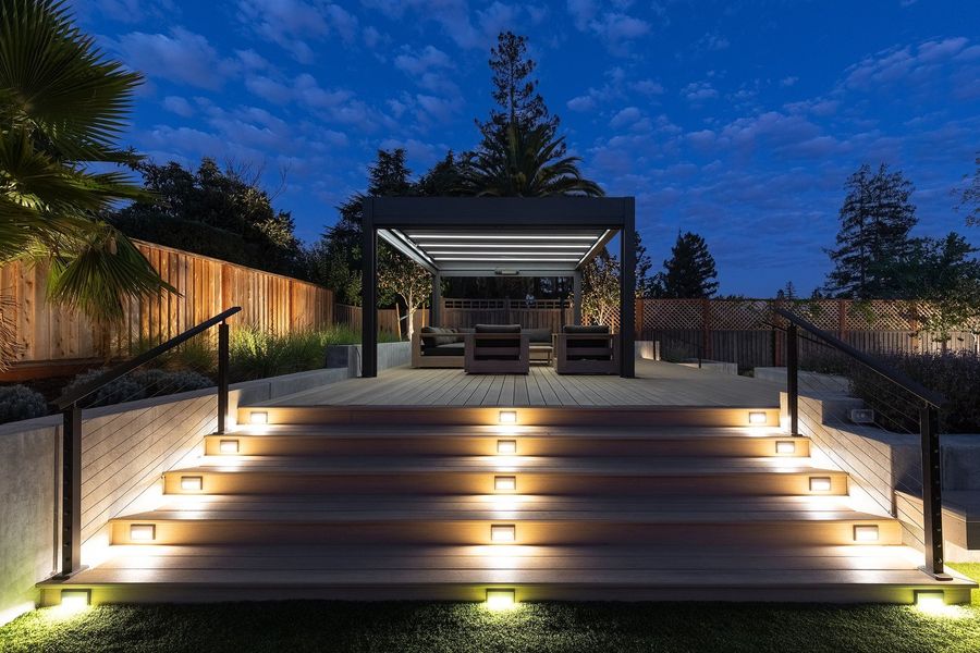 Blue-hour view of a lit stair with recessed riser lights and the lit pergola above