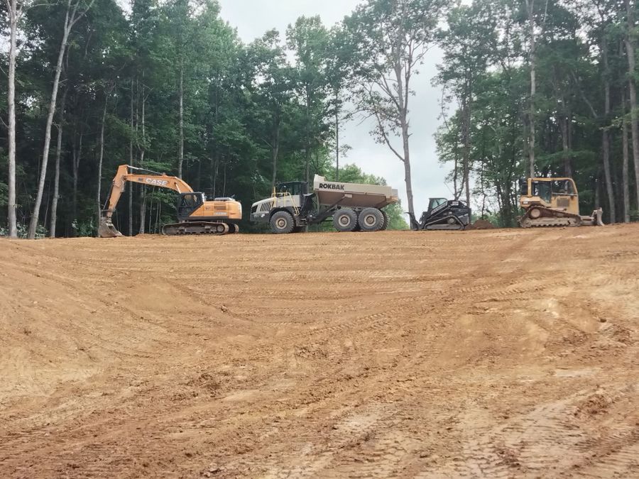 Excavator, articulated dump truck and tracked machines lined up on a cleared dirt site