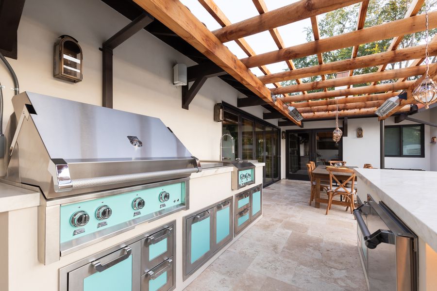 Built-in grill and sink in an outdoor kitchen with glazed turquoise tile cabinet fronts