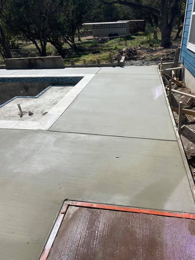 New concrete slab poured along the edge of a backyard pool